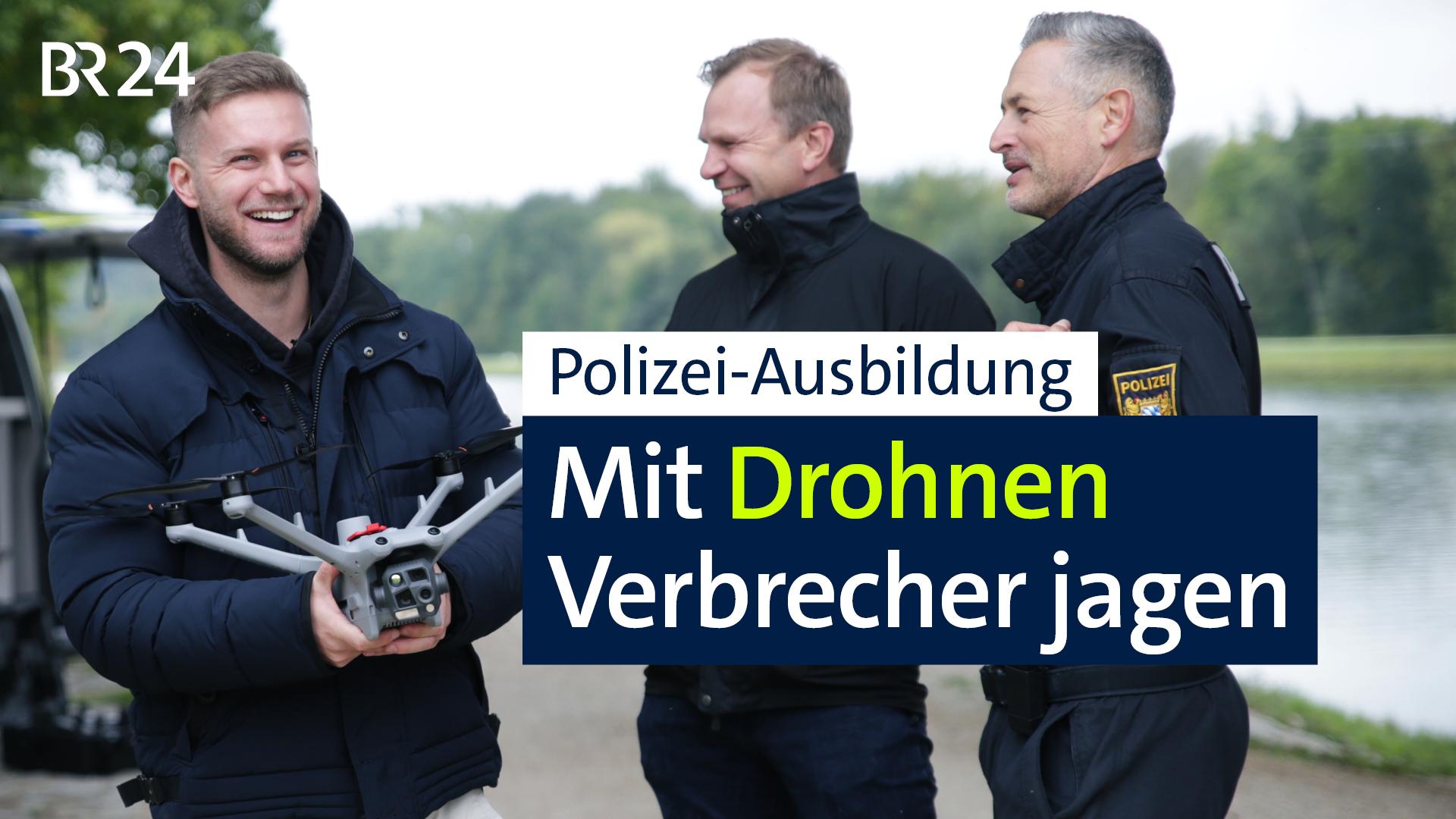 Zwei Beamte stehen neben einem Polizisten mit einer Drohne in der Hand
