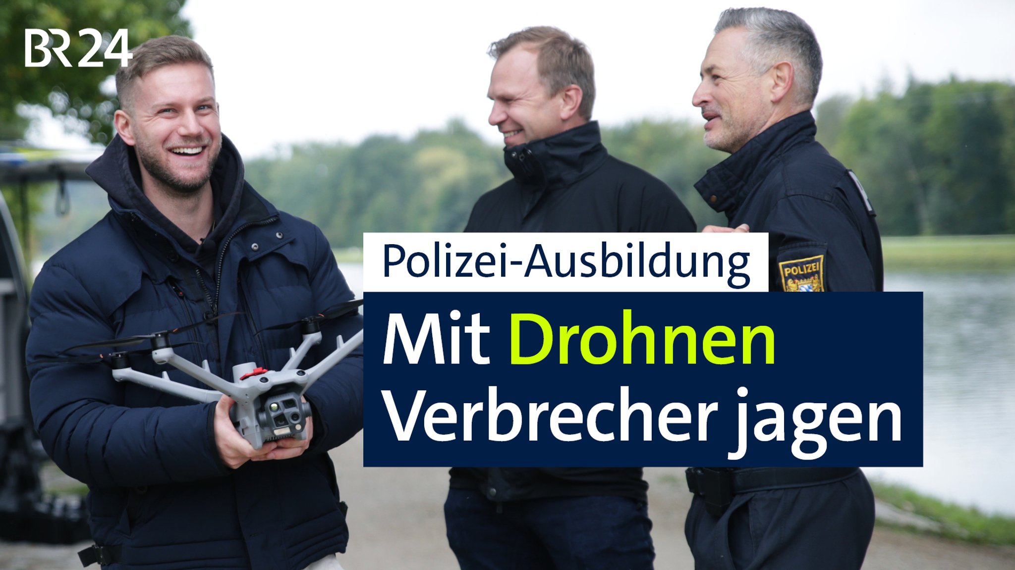 Zwei Beamte stehen neben einem Polizisten mit einer Drohne in der Hand