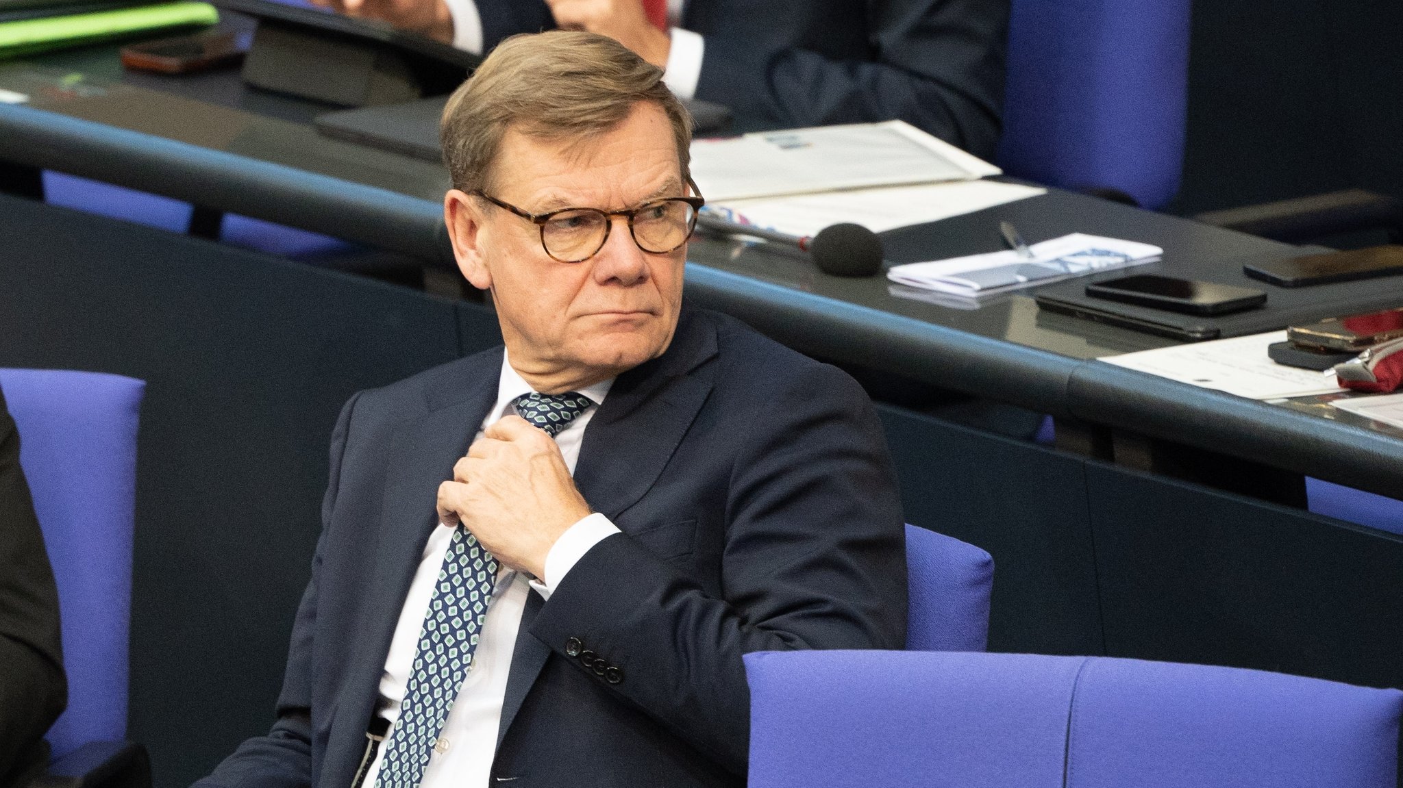 Johann Wadephul (CDU), Bundesaußenminister, sitzt in einer Debatte im Deutschen Bundestag mit einer Hand an seiner Krawatte und schaut sich um
