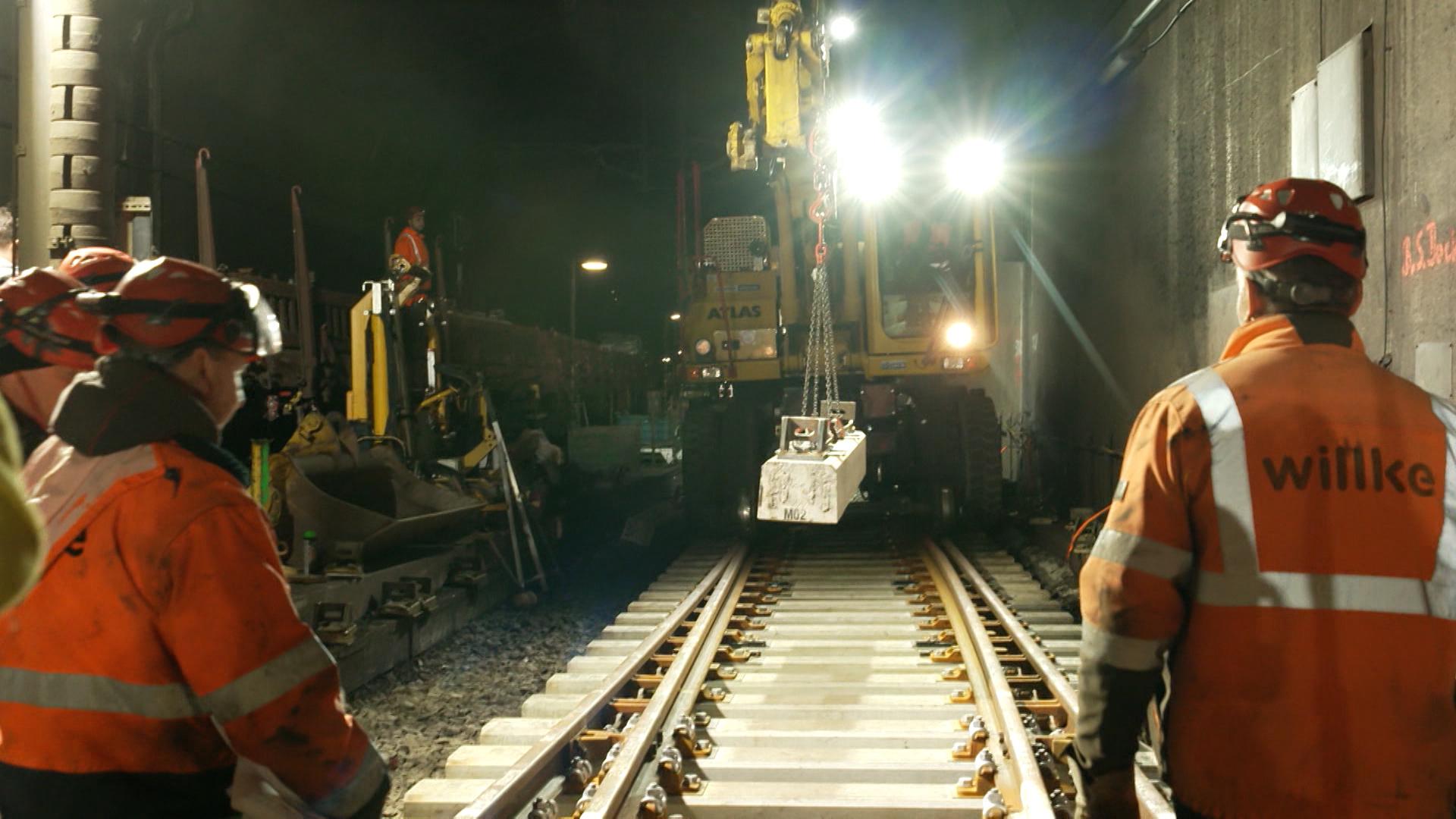 Ein Zweiwegebagger bringt eine neue Betonsschwelle zum Einbau einer Weiche im Bahnhof Isartor.