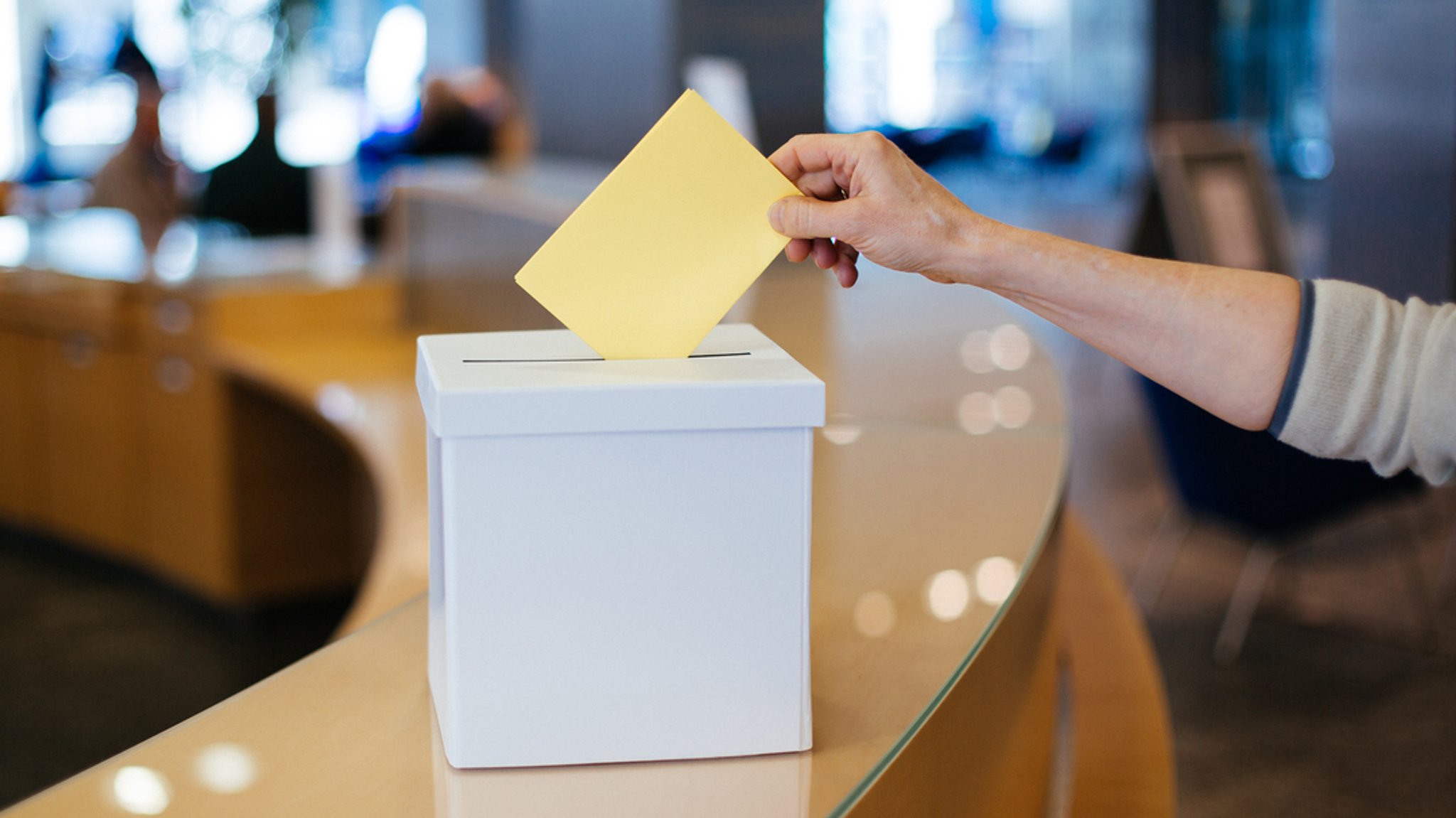 Jemand wirft einen Wahlschein in eine Wahlurne.