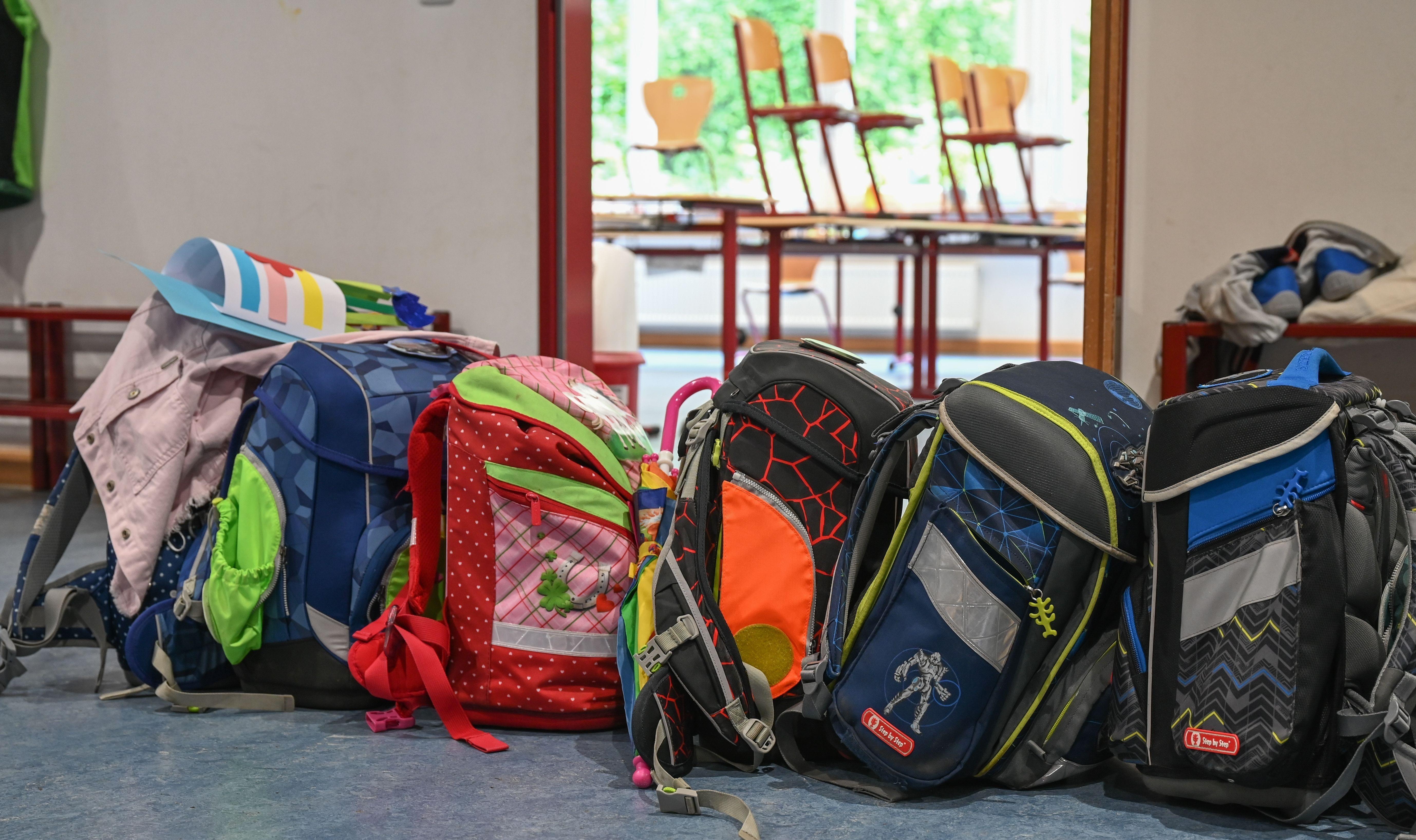 (Symbolbild) Schulranzen stehen vor einem geöffneten Klassenzimmer. 