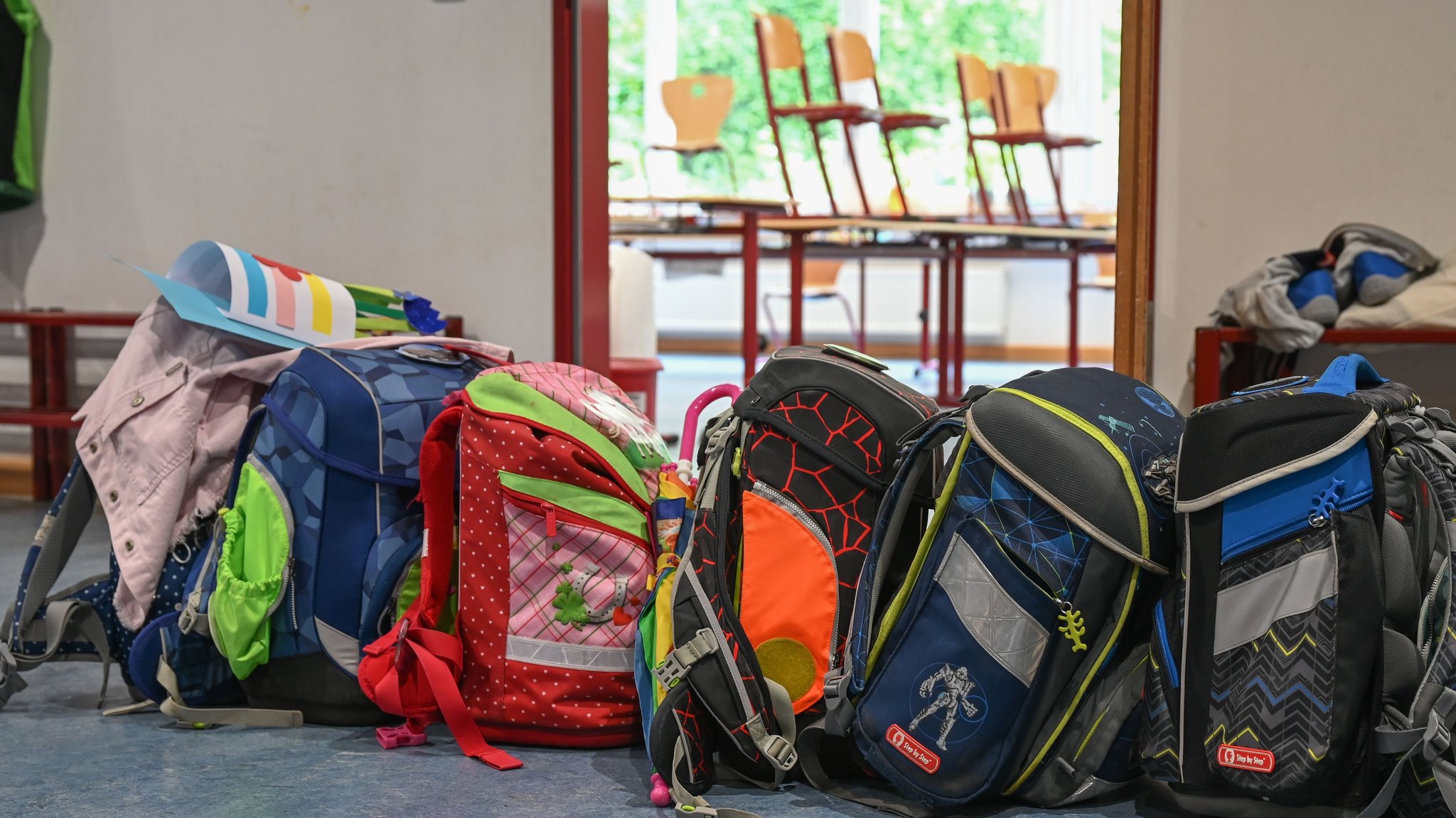 (Symbolbild) Schulranzen stehen vor einem geöffneten Klassenzimmer. 