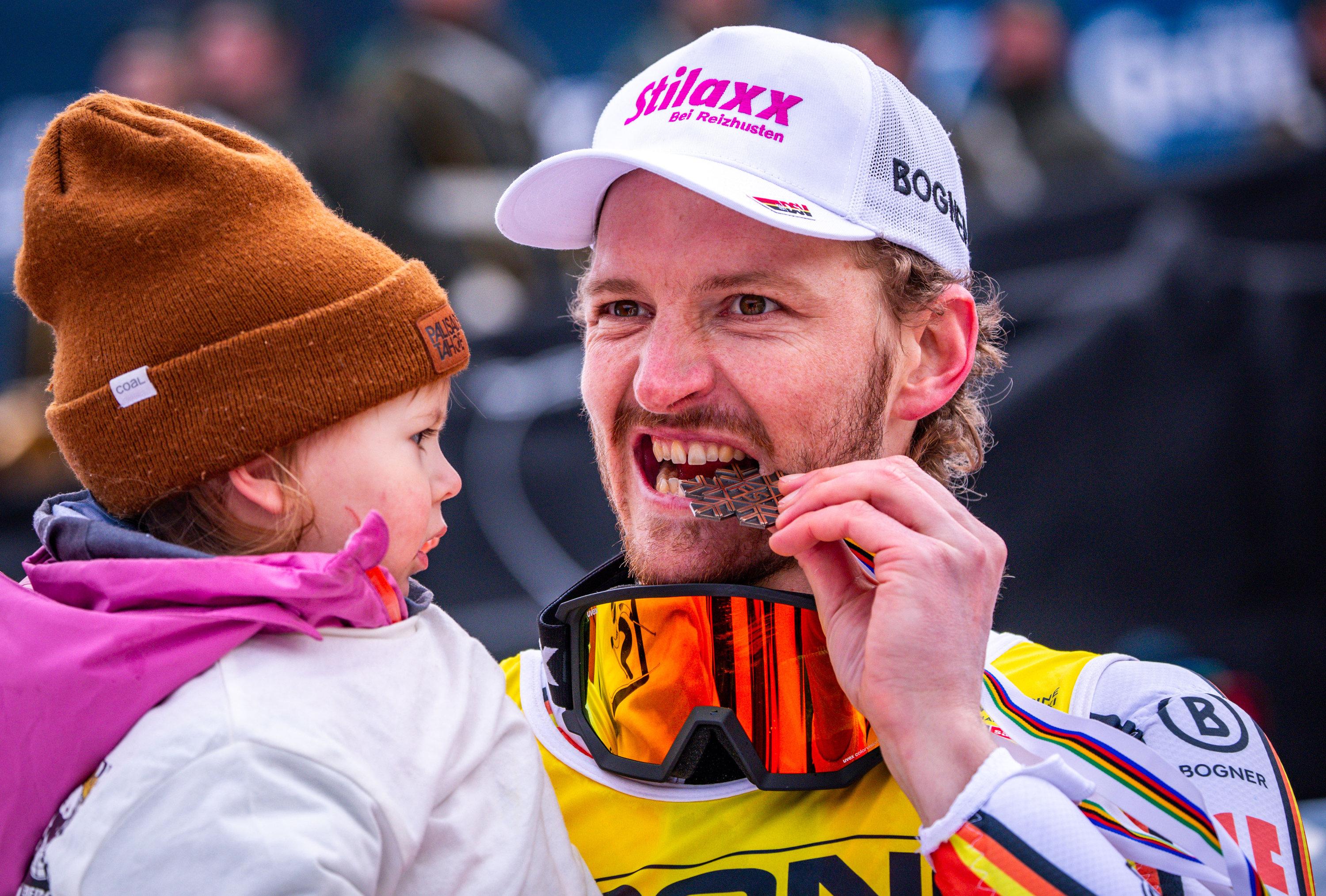 16.02.2025, Österreich, Saalbach-Hinterglemm: Ski alpin: Weltmeisterschaft, Slalom, Herren, 2. Durchgang, Linus Straßer aus Deutschland jubelt nach dem Gewinn der Bronzemedaille mit seinem Kind. 