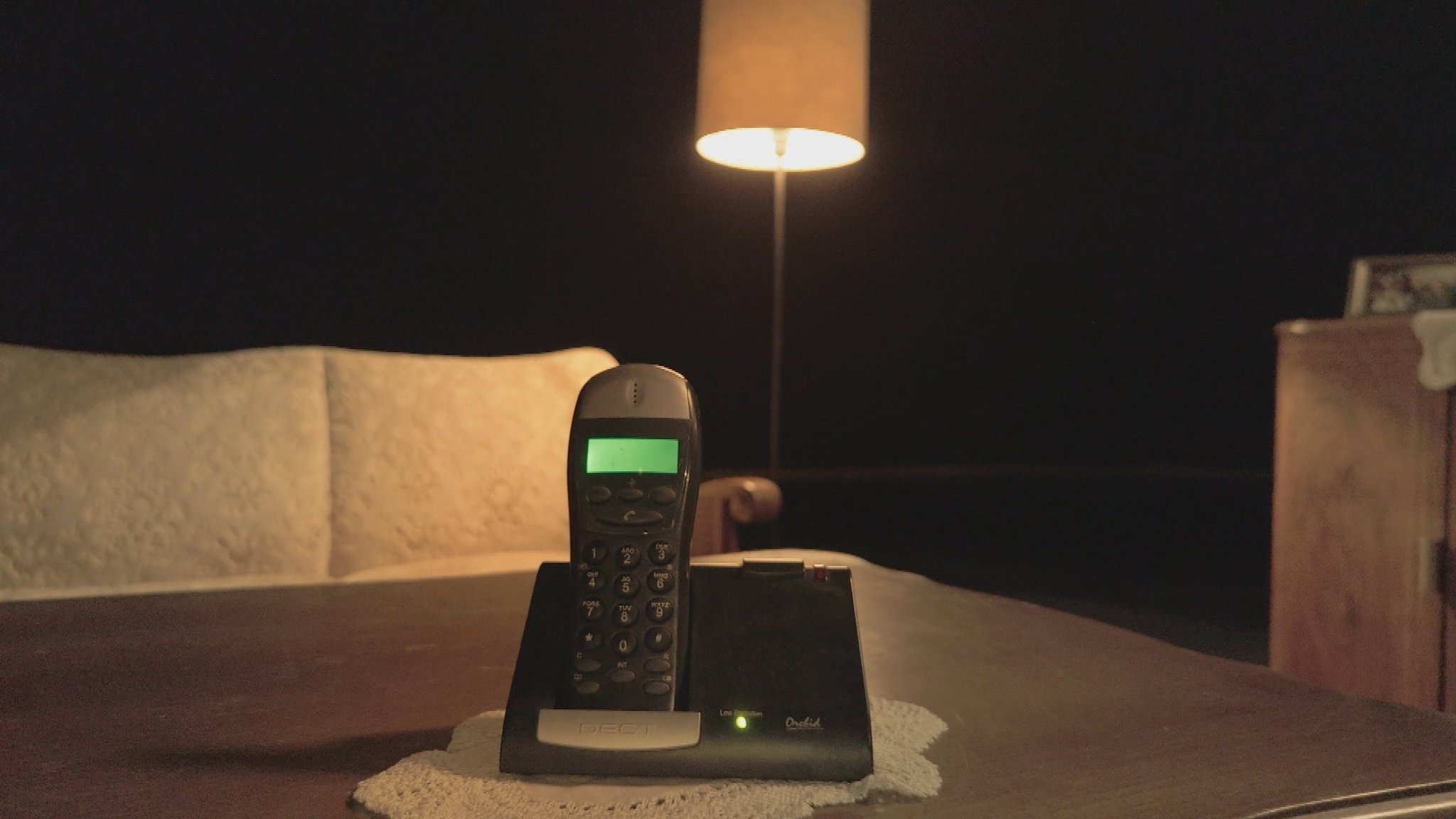 Ein Telefon steht auf einem Tisch in einem dunklen Wohnzimmer. 