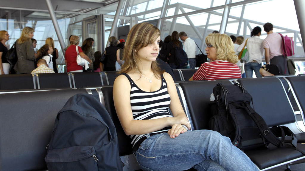 Junge Frau sitzt und wartet am Flughafen.