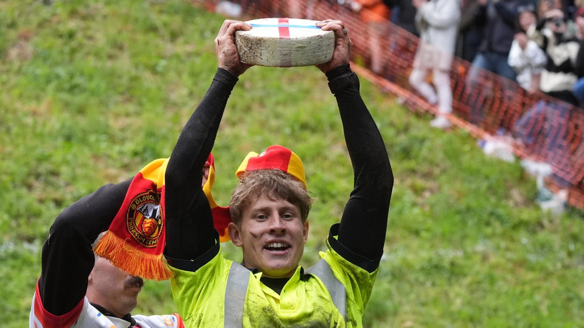 Tom Kopke, der Sieger des ersten Rennens, hebt einen Double-Gloucester-Käse