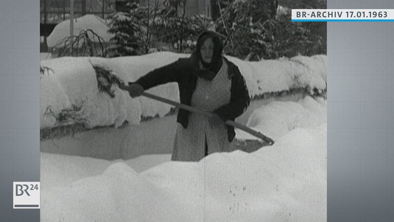 Frau beim Schneeräumen im knietiefen Schnee