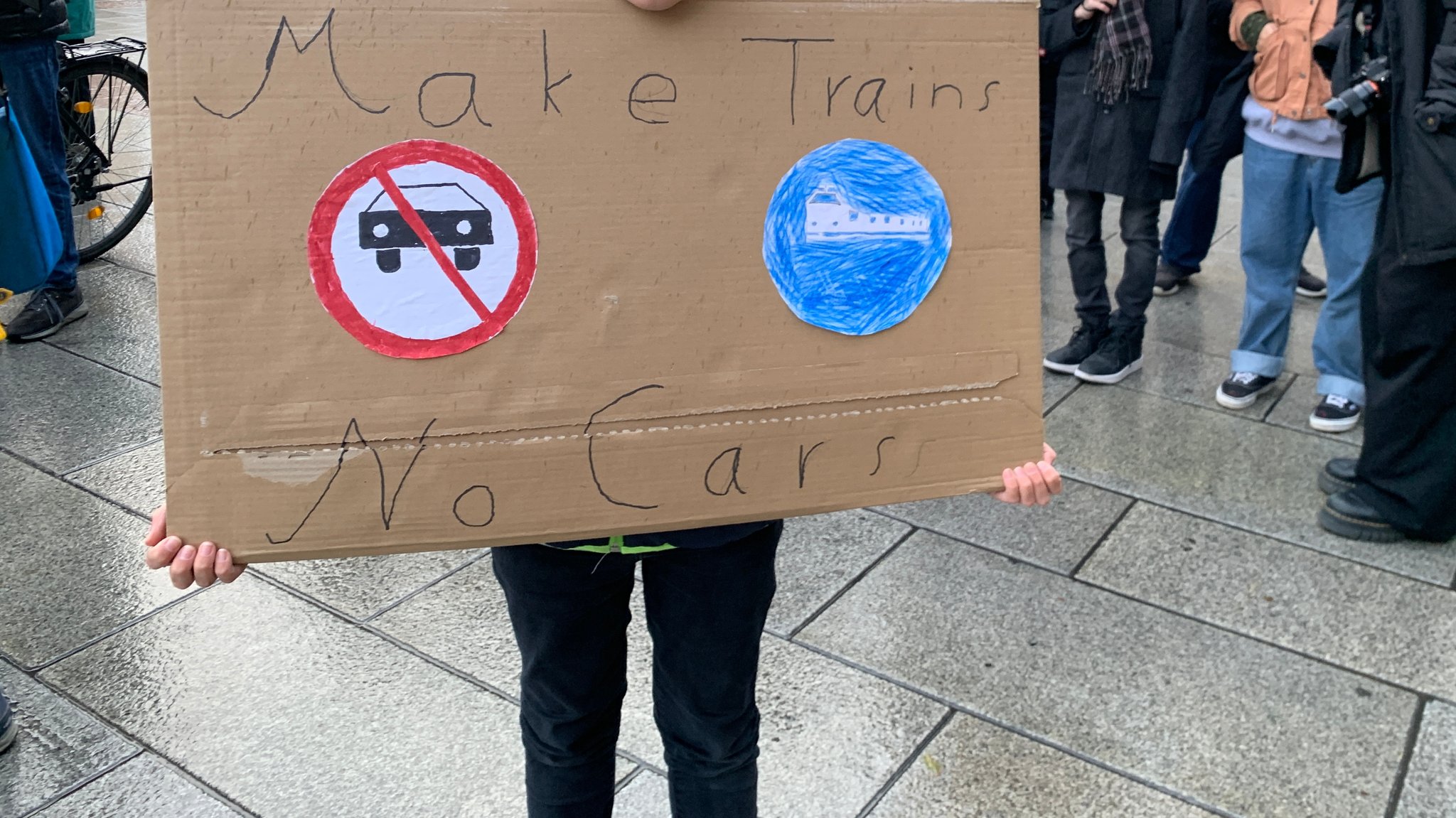 Eine junge Demo-Teilnehmerin hält ein Schild mit dem Schriftzug "Make Trains no Cars"