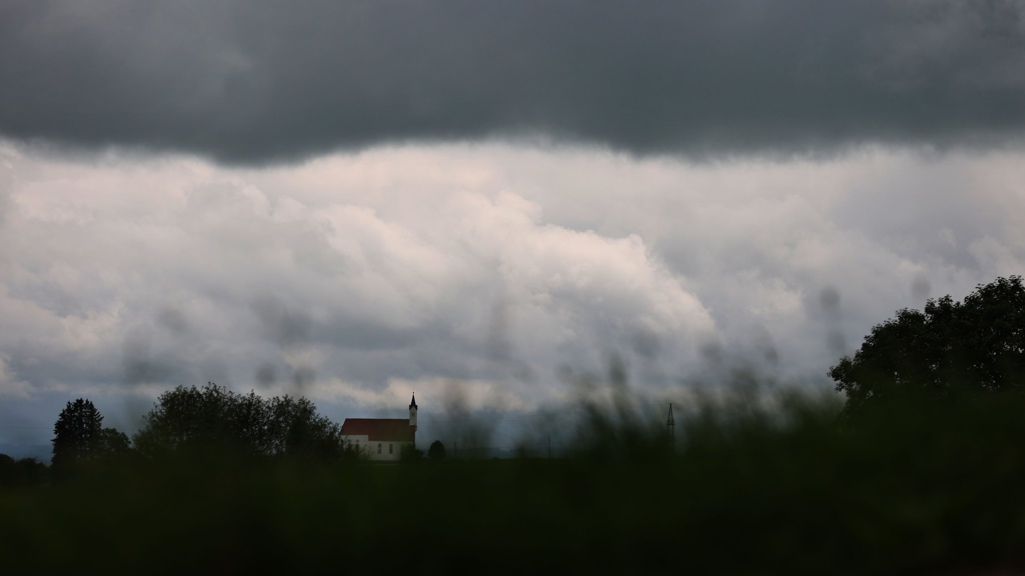 Wolken ziehen über die am Alpenrand gelegene Wallfahrtskirche Sankt Alban.