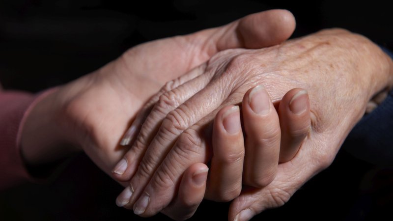 Hand eines jungen Menschen hält die Hand eines älteren Menschen