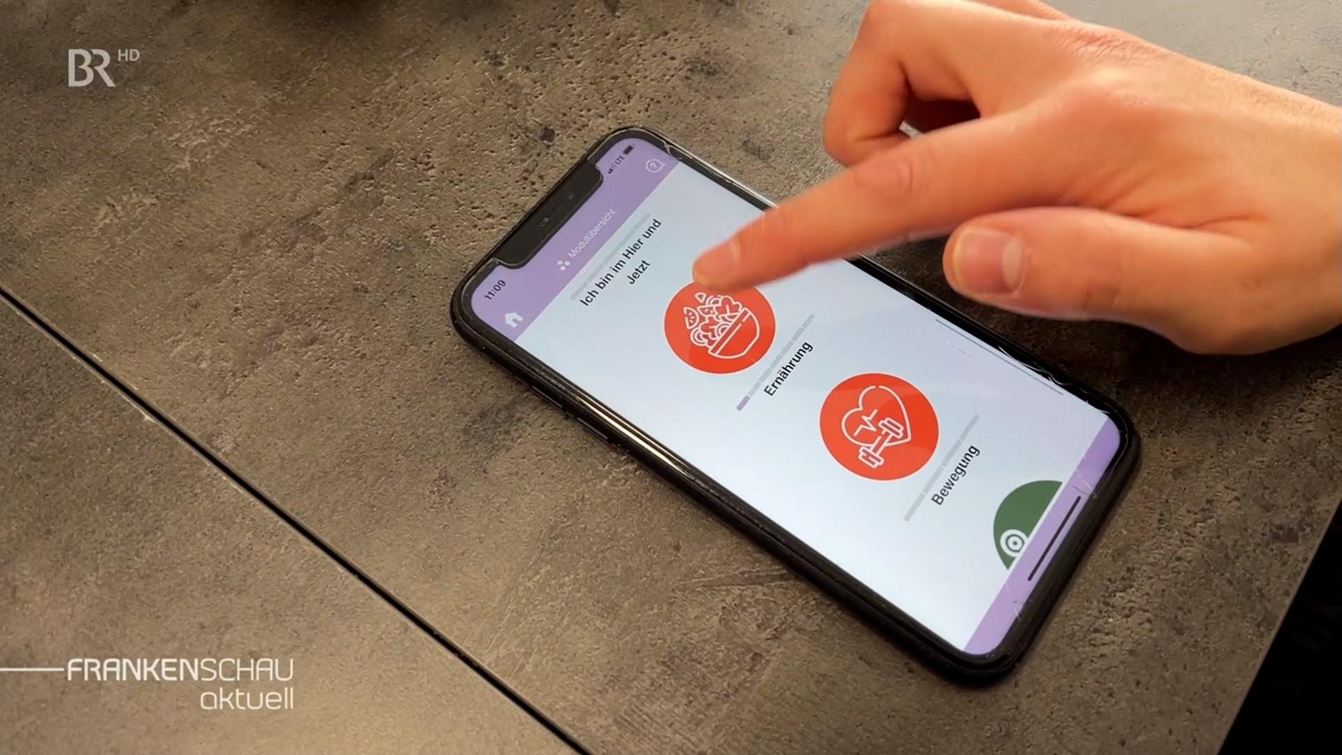 Ein Finger tippt auf das Display eines Smartphones. 
