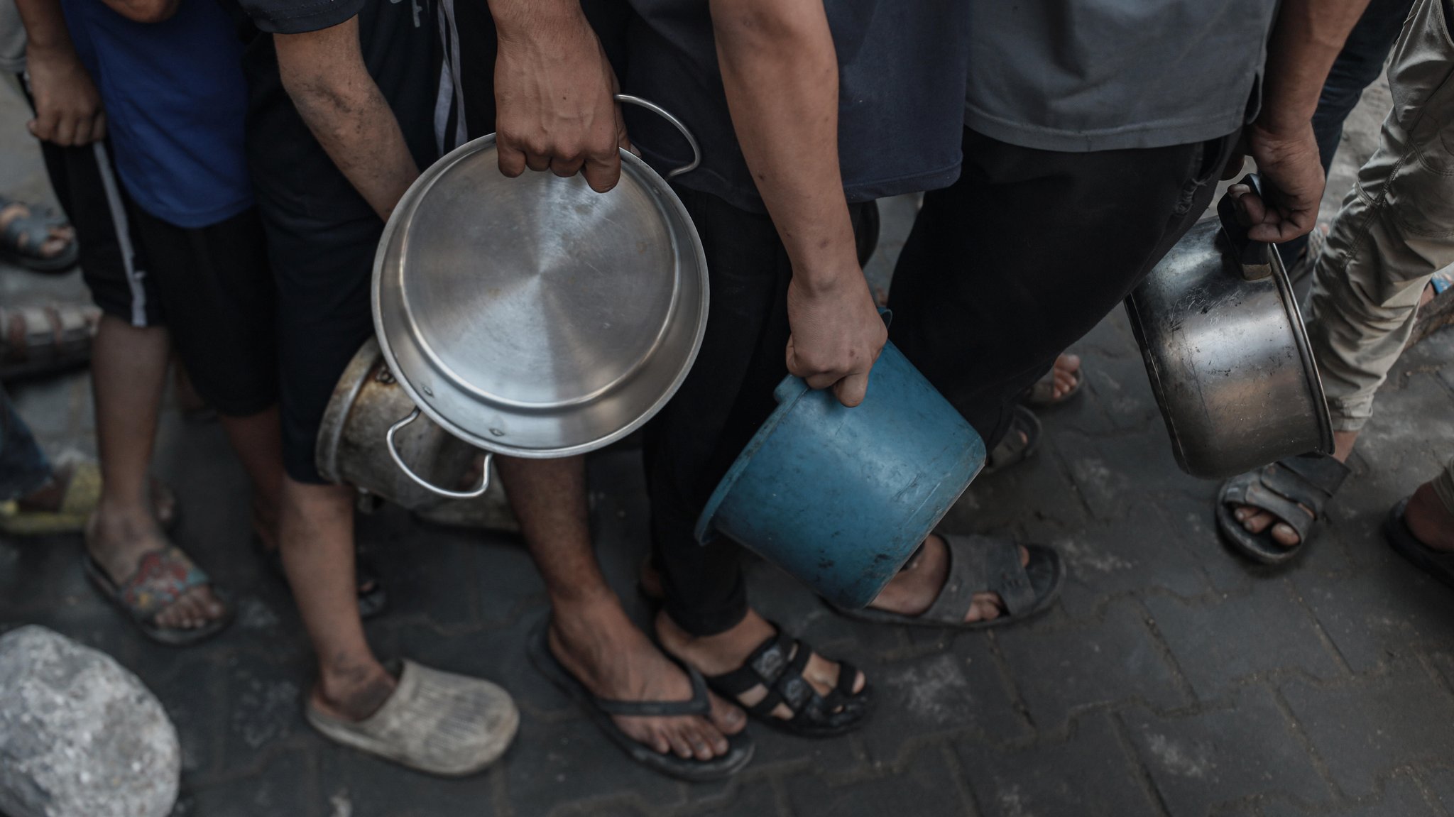 Menschen stehen mit Töpfen und Schüsseln an einer Essensausgabe im Gazastreifen an (Symbolbild)
