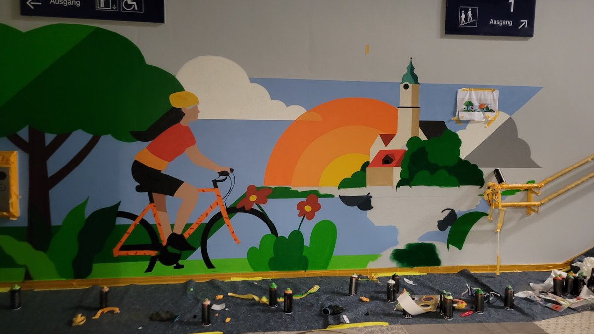 Eine Graffiti einer Radfahrenden Frau in einer blühenden Landschaft in einer Bahnunterführung