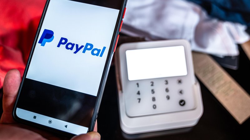 Symbolbild: Ein Kunde bezahlt Kleidung in einem Geschäft mit Paypal Pay per Smartphone. | Bild: picture alliance / CHROMORANGE | Michael Bihlmayer Symbolbild: Ein Kunde bezahlt Kleidung in einem Geschäft mit Paypal Pay per Smartphone.