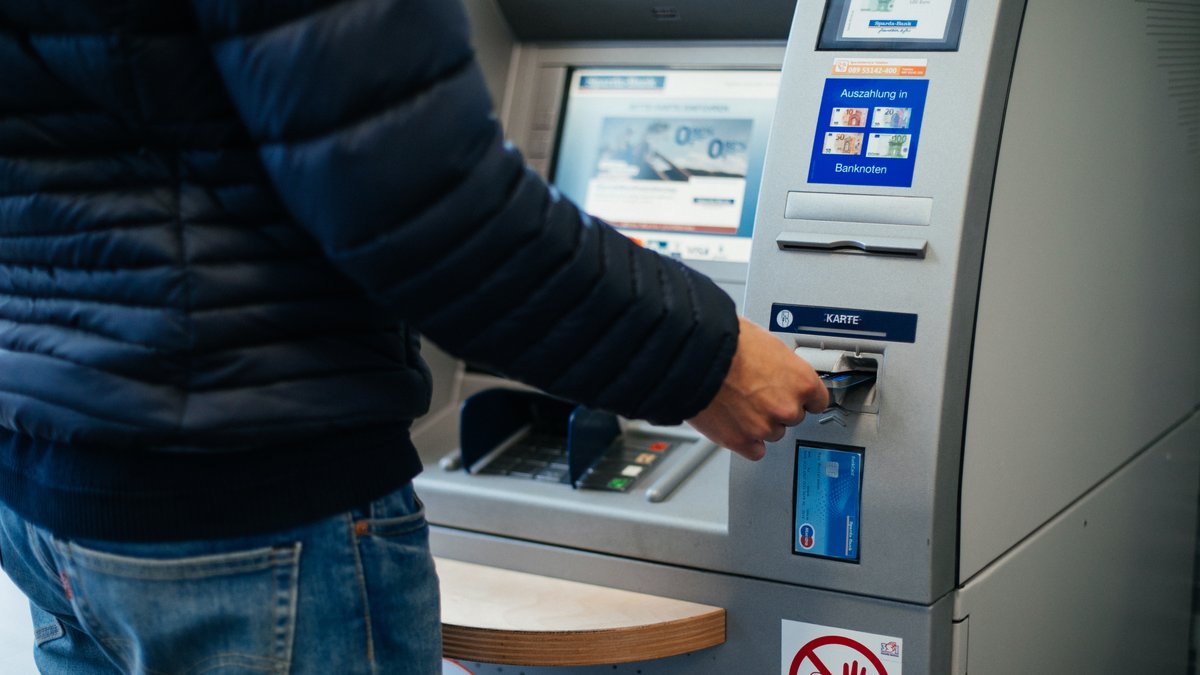 Ein Mann schiebt seine Bankkarte in den Geldautomaten.