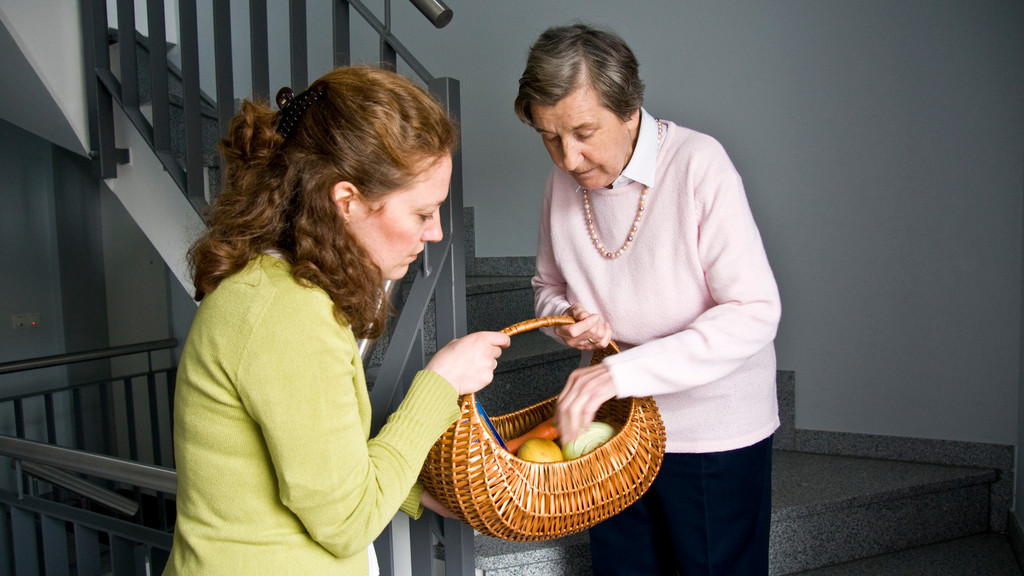 Eine Frau hilft einer älteren Dame.