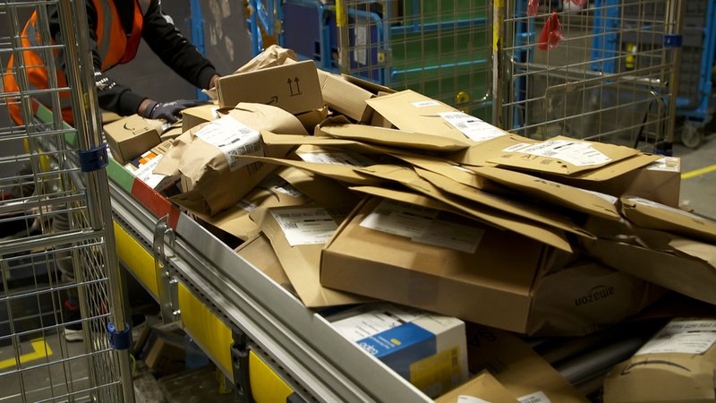 Päckchen und Pakte stapeln sich auf einem Förderband. | Bild: BR Päckchen und Pakte stapeln sich auf einem Förderband.