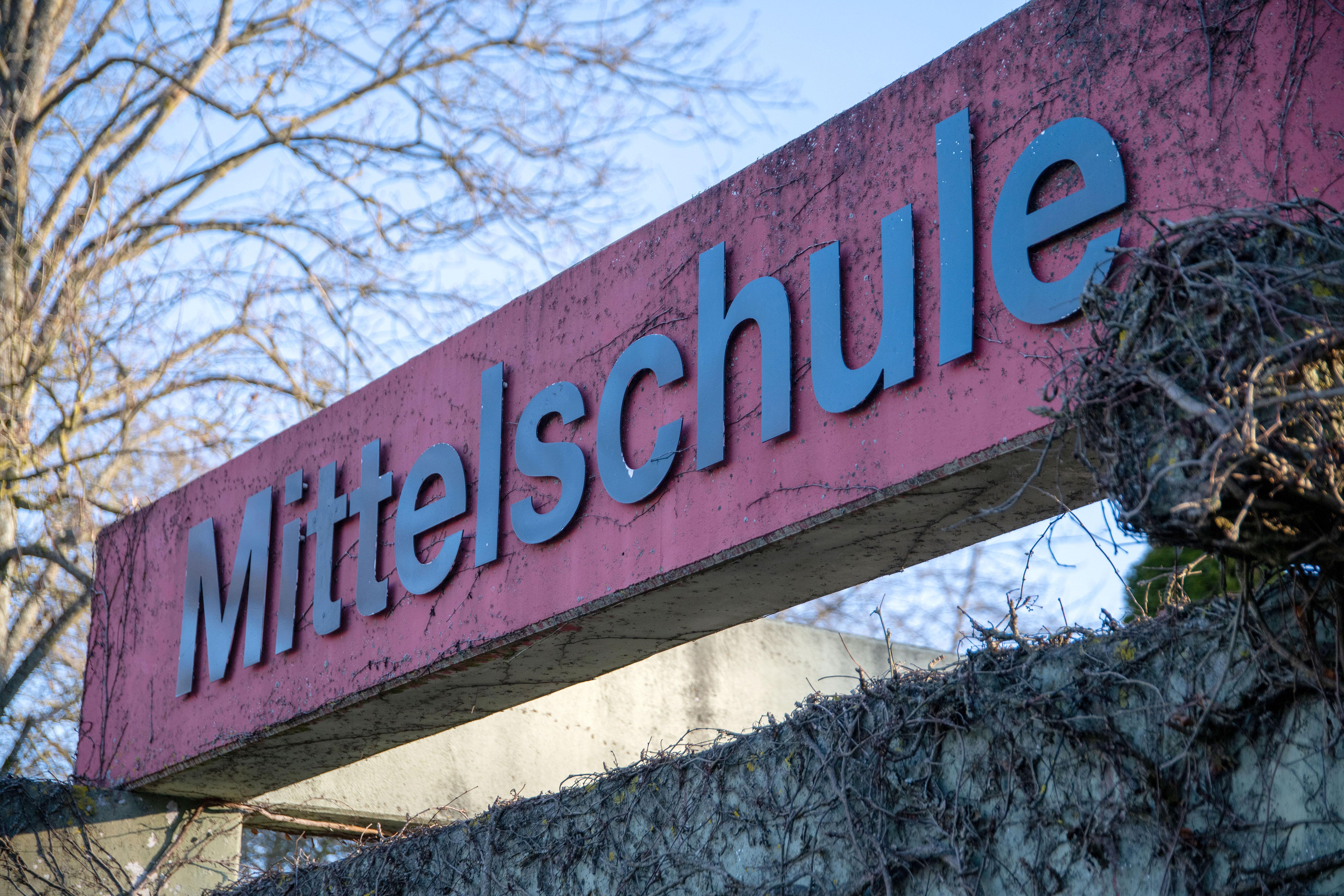 (Symbolbild) Der Schriftzug "Mittelschule" ist an der Mauer eines Schulhofs zu lesen.
