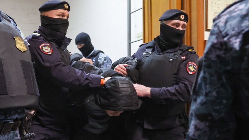 Russische Polizisten führen einen Terrorverdächtigen ab.