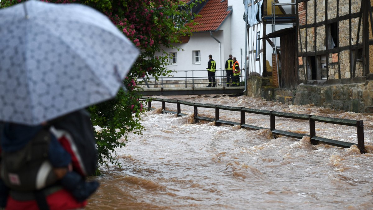 Feuerwehrleute beobachten die über die Ufer getretene Losse. Schwere Regenfälle hatten seinerzeit zahlreiche Bäche in Nordhessen zum Überlaufen gebracht. 