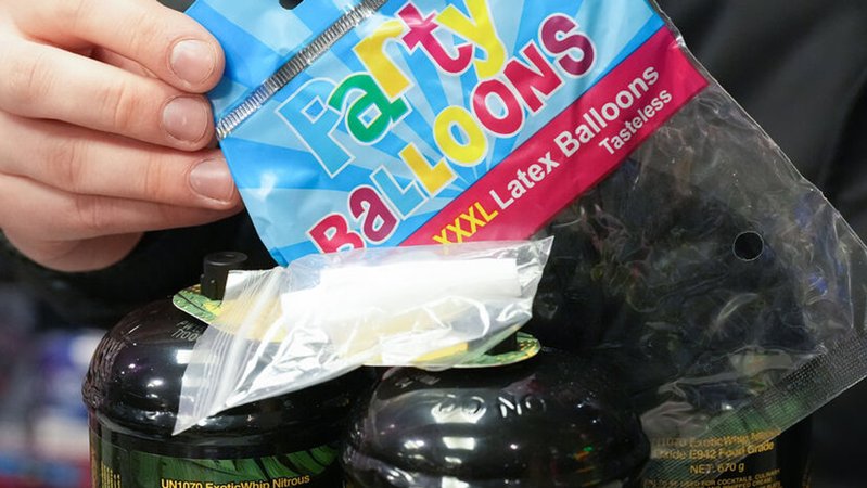 Archivbild: Ein Mitarbeiter hält eine Tüte mit Luftballons, im Vordergrund drei Dosen Lachgas und ein Mundstück | Bild: dpa-Bildfunk/Marcus Brandt Archivbild: Ein Mitarbeiter hält eine Tüte mit Luftballons, im Vordergrund drei Dosen Lachgas und ein Mundstück