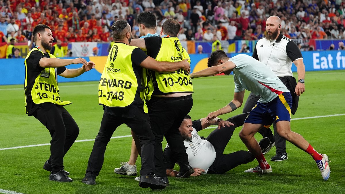 Alvaro Morata wird beim Versuch, einen Flitzer zu stellen, von einem Ordner am Bein erwischt