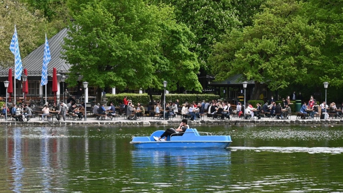 Zwei Männer fahren mit einem Tretboot auf dem Kleinhesseloher See im Englischen Garten vor dem Seehaus Biergarten.