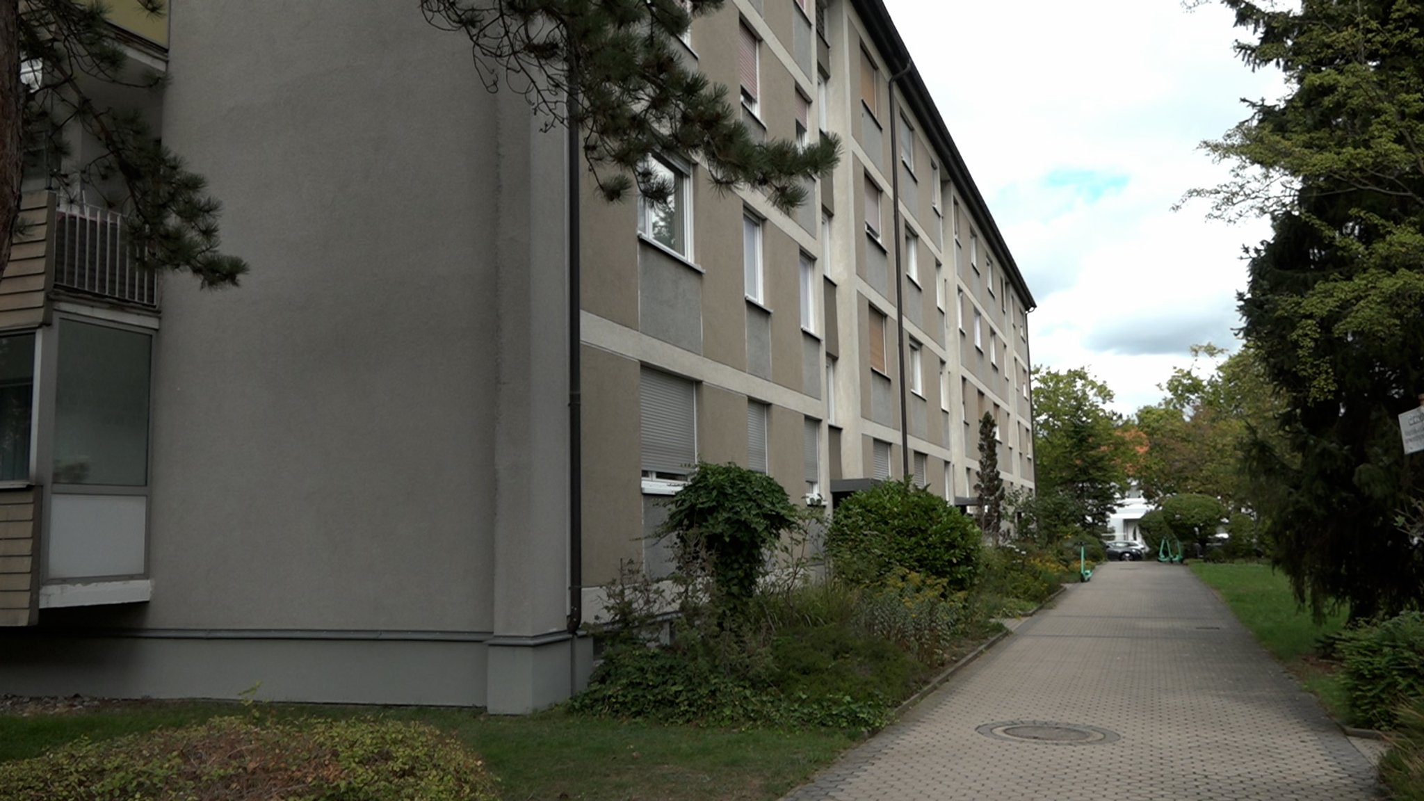 Ein Weg entlang eines grauen Mehrfamilienhauses | Bild: BR Ein Weg entlang eines grauen Mehrfamilienhauses