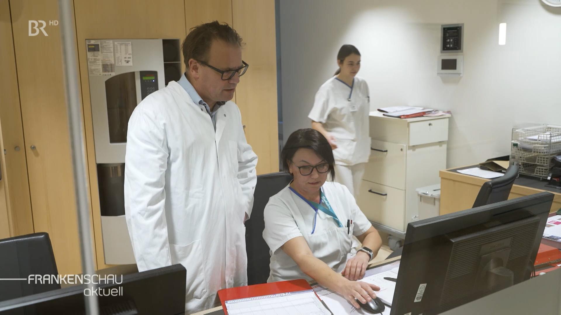 Ein Mann und zwei Frauen in einem Stationszimmer 