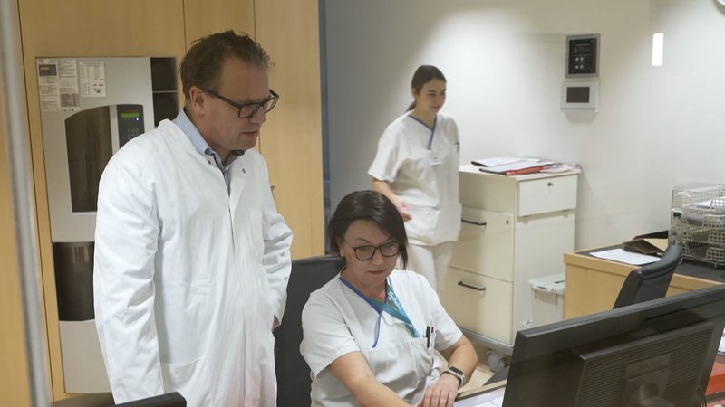 Ein Mann und zwei Frauen in einem Stationszimmer | Bild: BR Ein Mann und zwei Frauen in einem Stationszimmer