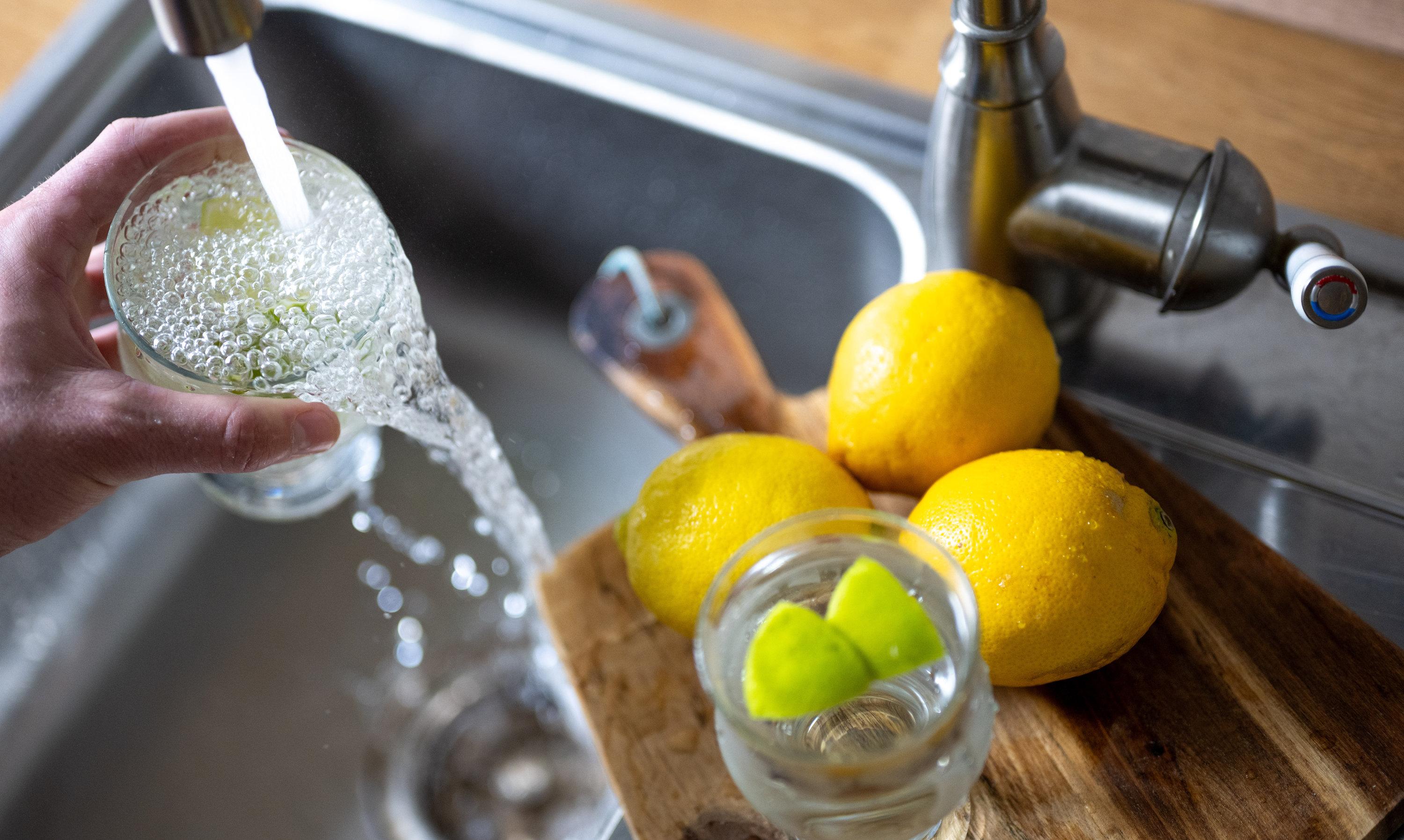 Wasser läuft aus einem Wasserhahn in ein Trinkglas. 