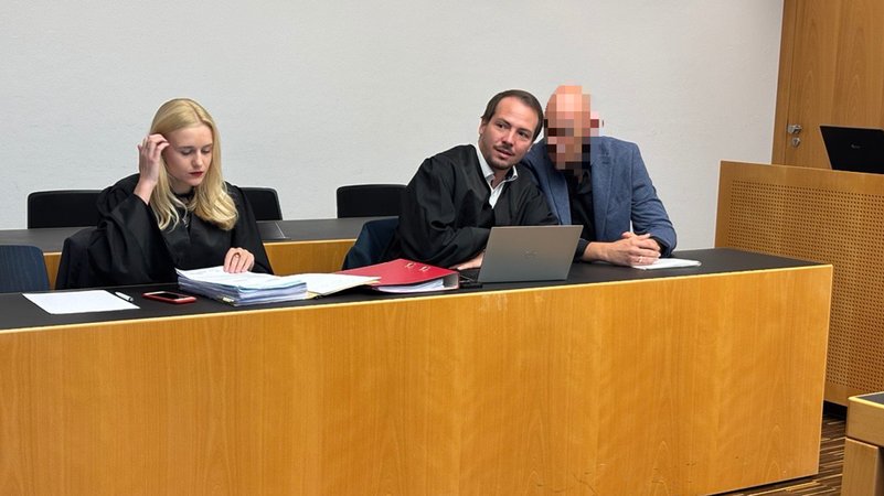 Der verpixelte Angeklagte mit seinen Strafverteidigern in einem Saal des Augsburger Landgerichts. | Bild: BR/ Barbara Leinfelder Der verpixelte Angeklagte mit seinen Strafverteidigern in einem Saal des Augsburger Landgerichts.