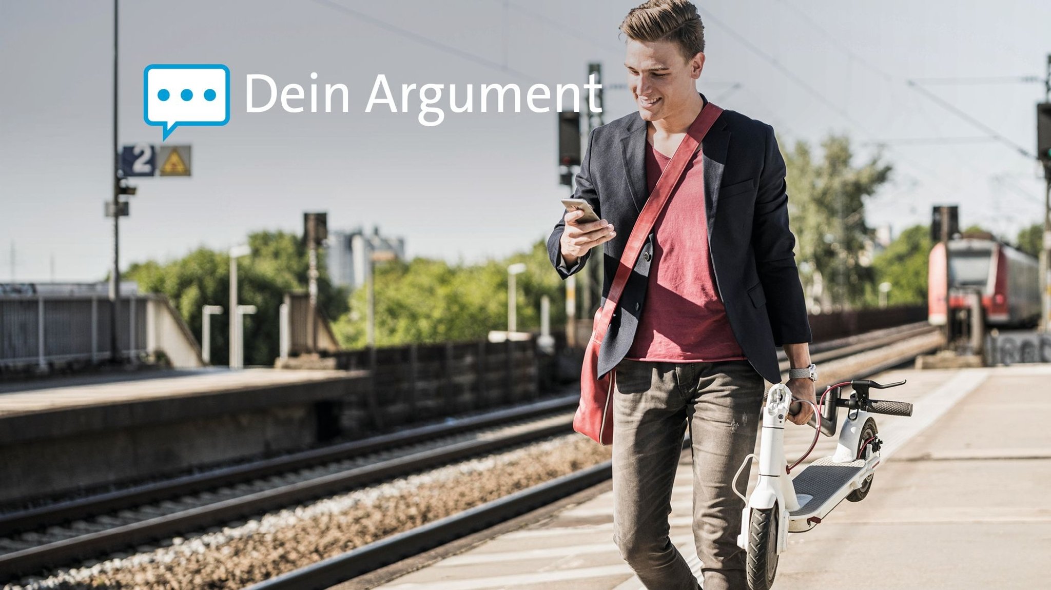 Mann mit E-Scooter in der Hand geht auf einem Bahnsteig