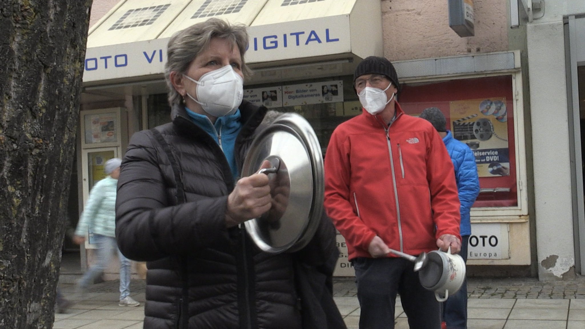 Eine Frau schlägt zwei Topfdeckel bei der Protestaktion des Wirtschaftsforums Freilassing