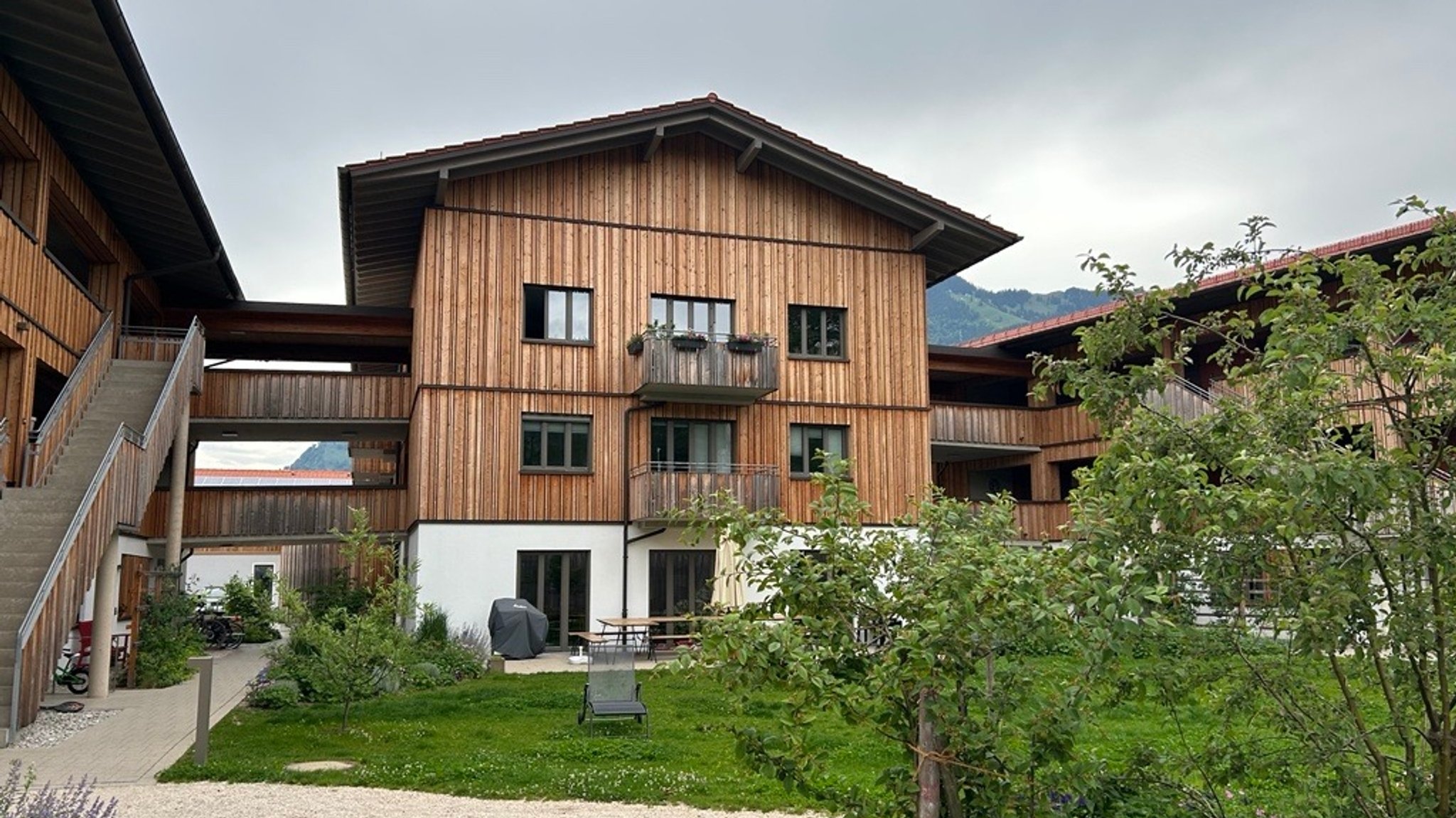 Ein Haus von vorne mit vielen Laubengängen und Holzschalung.