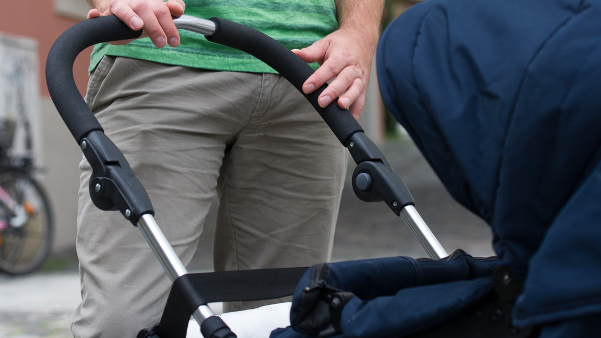 Mann steht an einem Kinderwagen (Symbolbild)