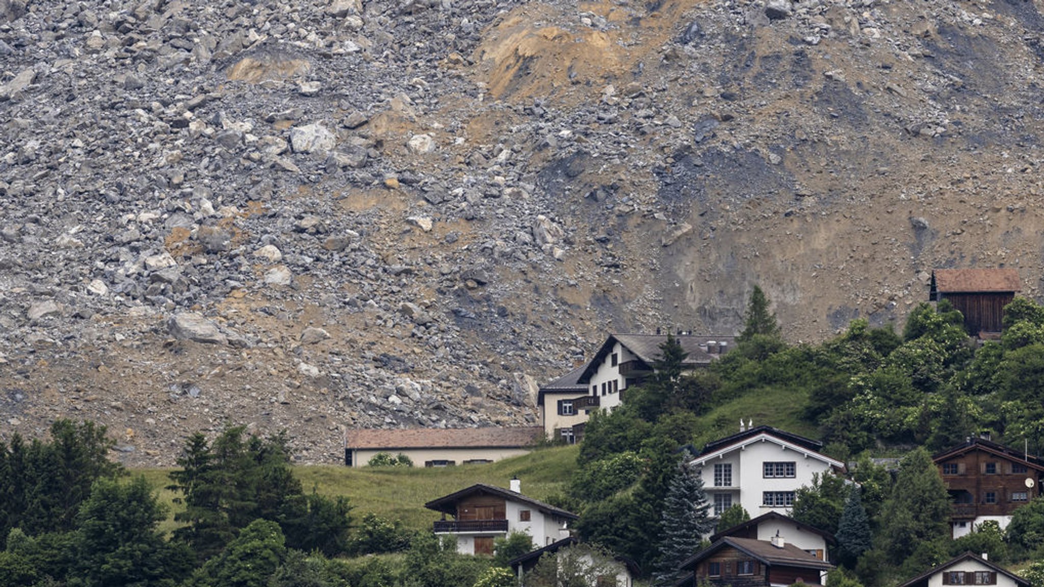 16.06.2023, Schweiz, Brienz-Brinzauls: Blick auf das Dorf Brienz-Brinzauls unterhalb des Felsrutsches. Ein gewaltiger Strom an Fels und Geröll hat nur knapp das Schweizer Bergdorf Brienz verfehlt. Ein großer Teil der absturzgefährdeten Felsmassen oberhalb der Siedlung sei in der Nacht auf Freitag (16.06.2023) heruntergekommen, meldete die zuständige Gemeinde Albula im Kanton Graubünden auf Twitter. Das Dorf wurde am 12. Mai evakuiert. Foto: Michael Buholzer/KEYSTONE/dpa +++ dpa-Bildfunk +++