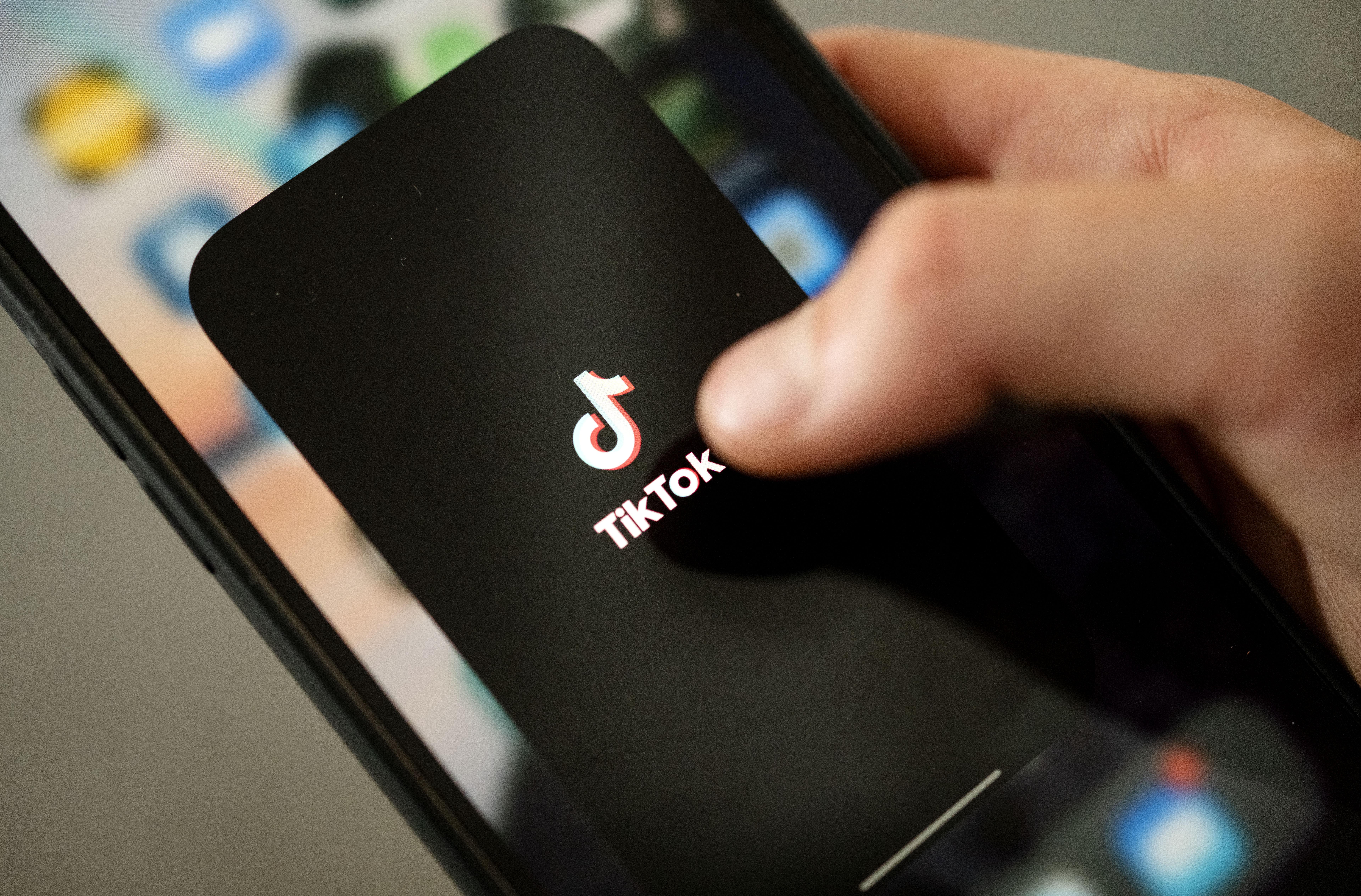Ein Teenager tippt auf das TikTok-Logo auf einem Smartphone.