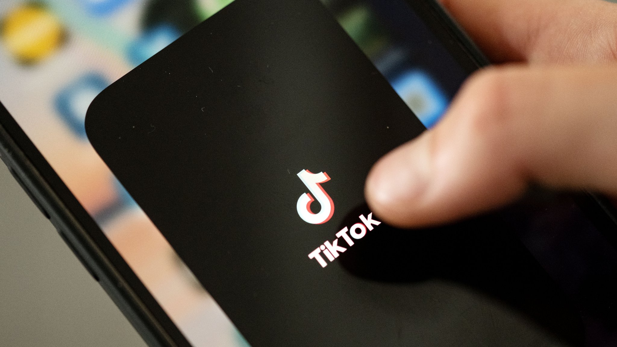 Ein Teenager tippt auf das TikTok-Logo auf einem Smartphone.