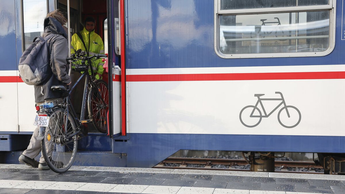 Ein Mann hebt sein Fahrrad in den Zug. 