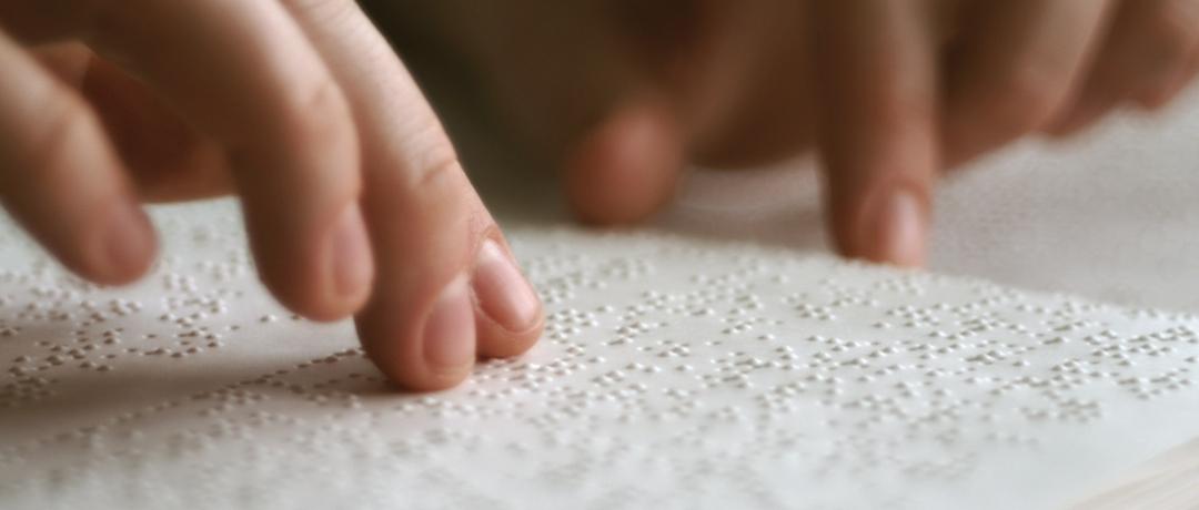 Hände ertasten die Blindenschrift. 