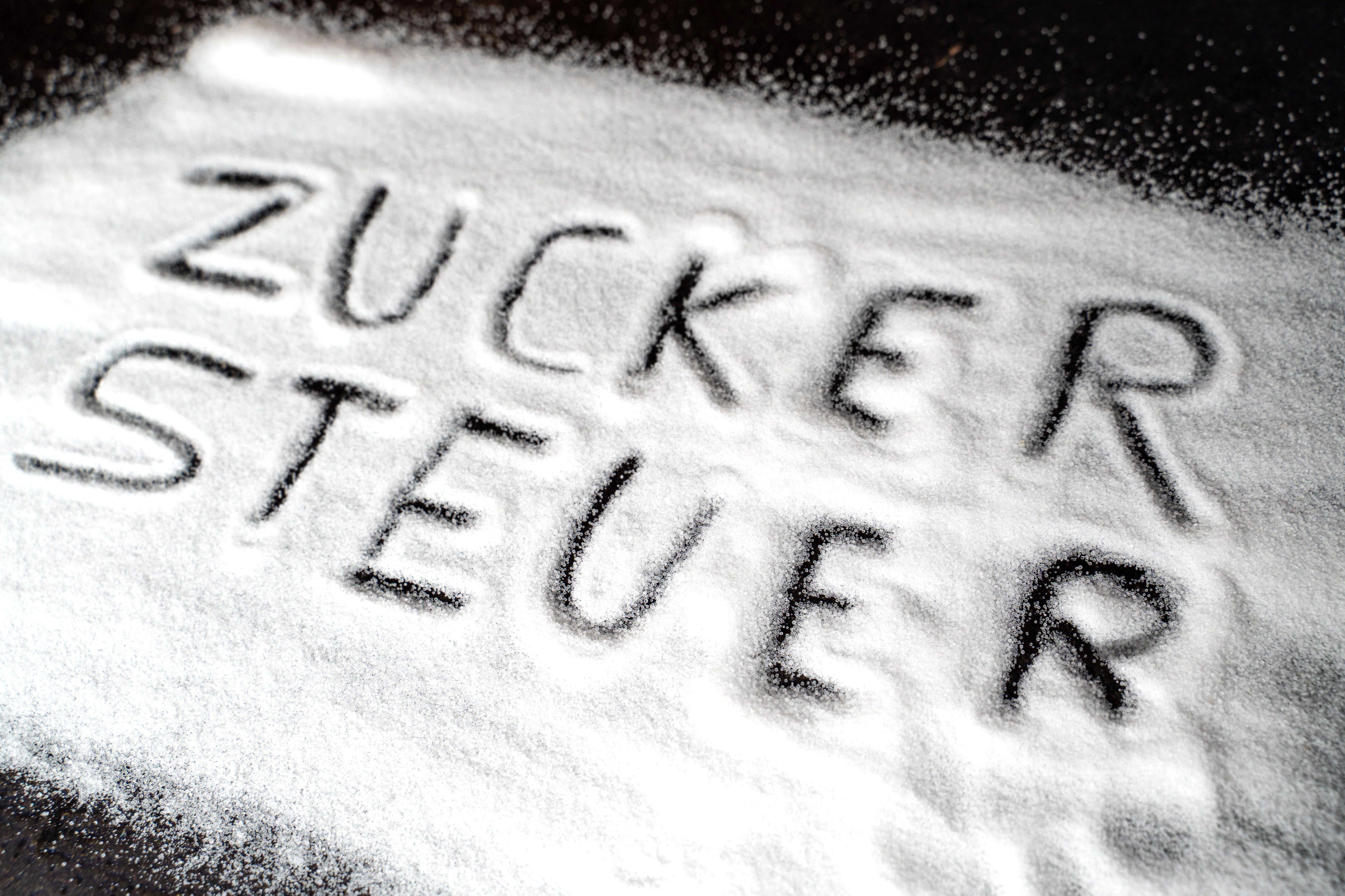 Symbolbild: Das Wort "Zuckersteuer" ist in eine Zuckerschicht geschrieben