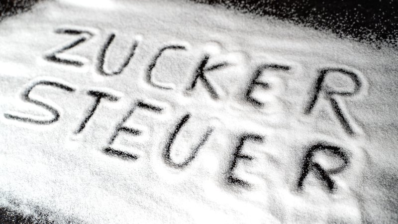 Symbolbild: Das Wort "Zuckersteuer" ist in eine Zuckerschicht geschrieben | Bild: picture alliance / CHROMORANGE | Michael Bihlmayer Symbolbild: Das Wort "Zuckersteuer" ist in eine Zuckerschicht geschrieben