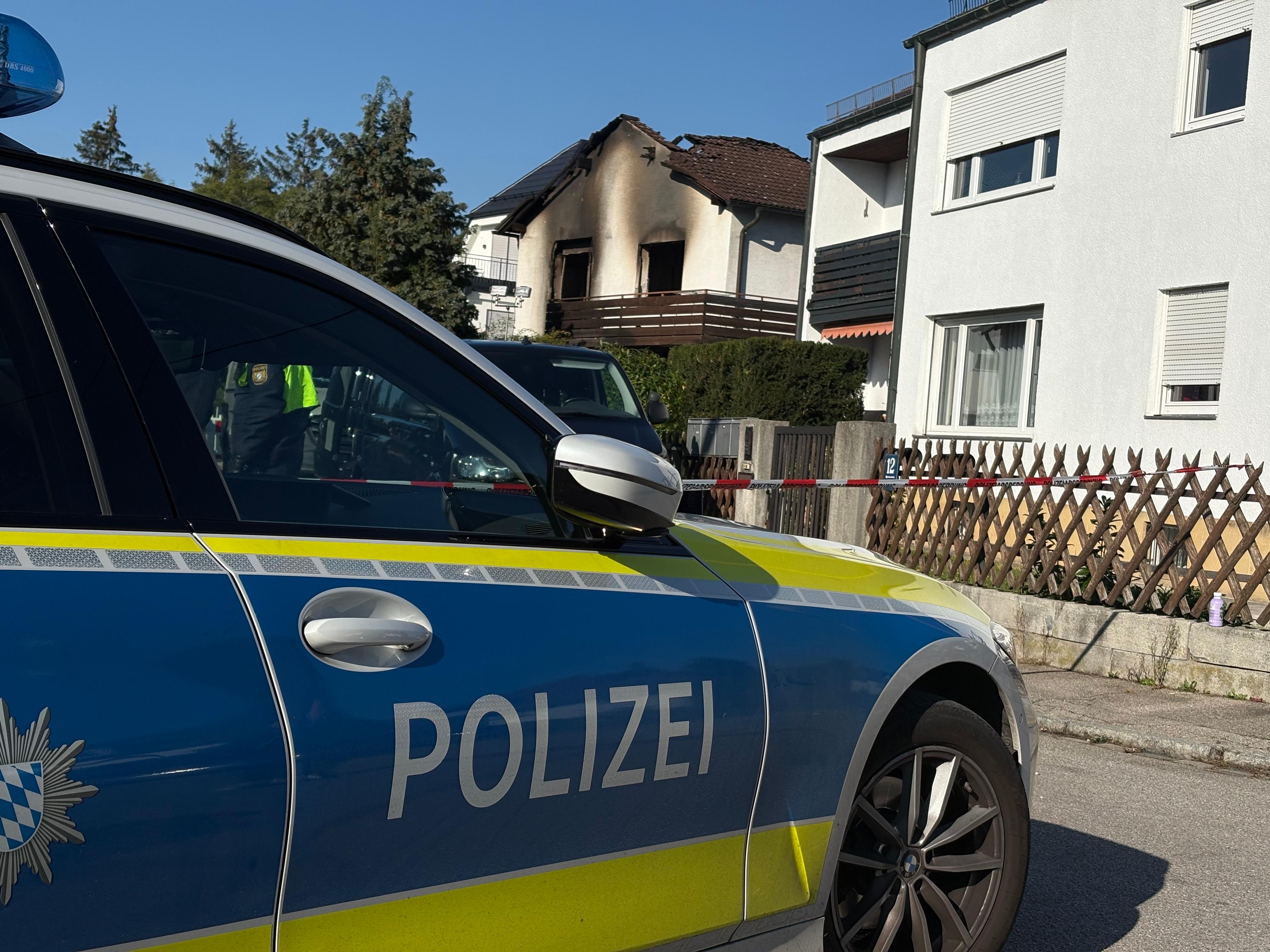 Polizei vor abgesperrtem Gehweg vor dem ausgebrannten Einfamilienhaus.