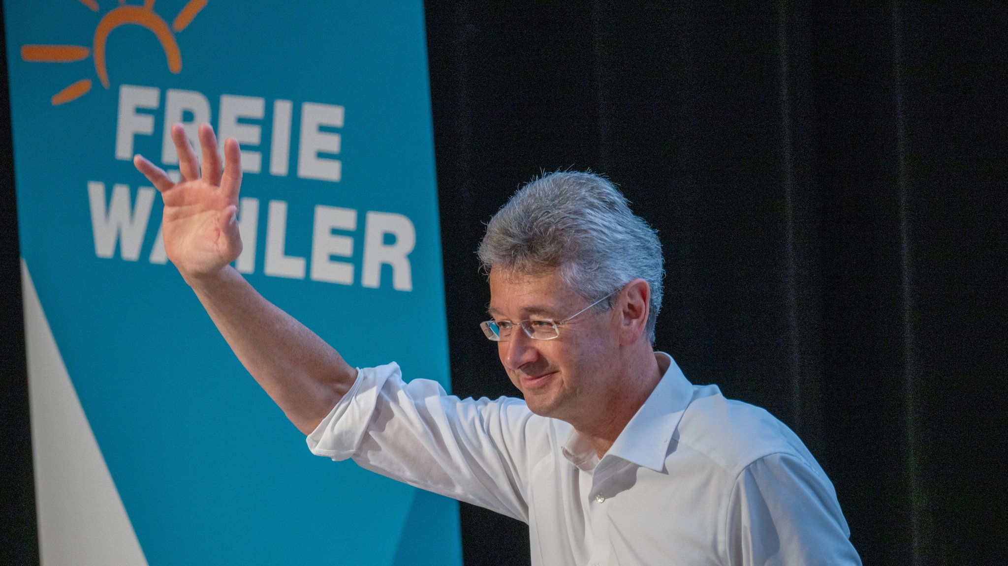 Michael Piazolo winkt, während hinter ihm das Logo seiner Partei zu sehen ist. 