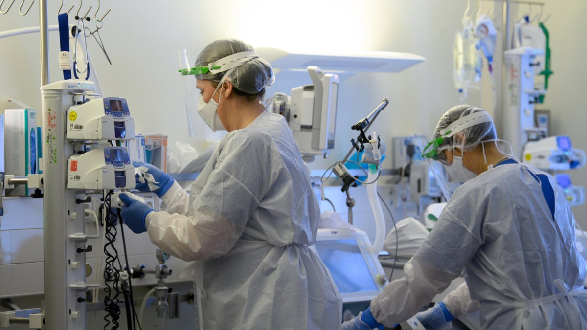 Intensivpflegerinnen sind in Schutzkleidungen auf der Covid-19-Intensivstation einer Klinik mit der Versorgung von Corona-Patienten beschäftigt. 