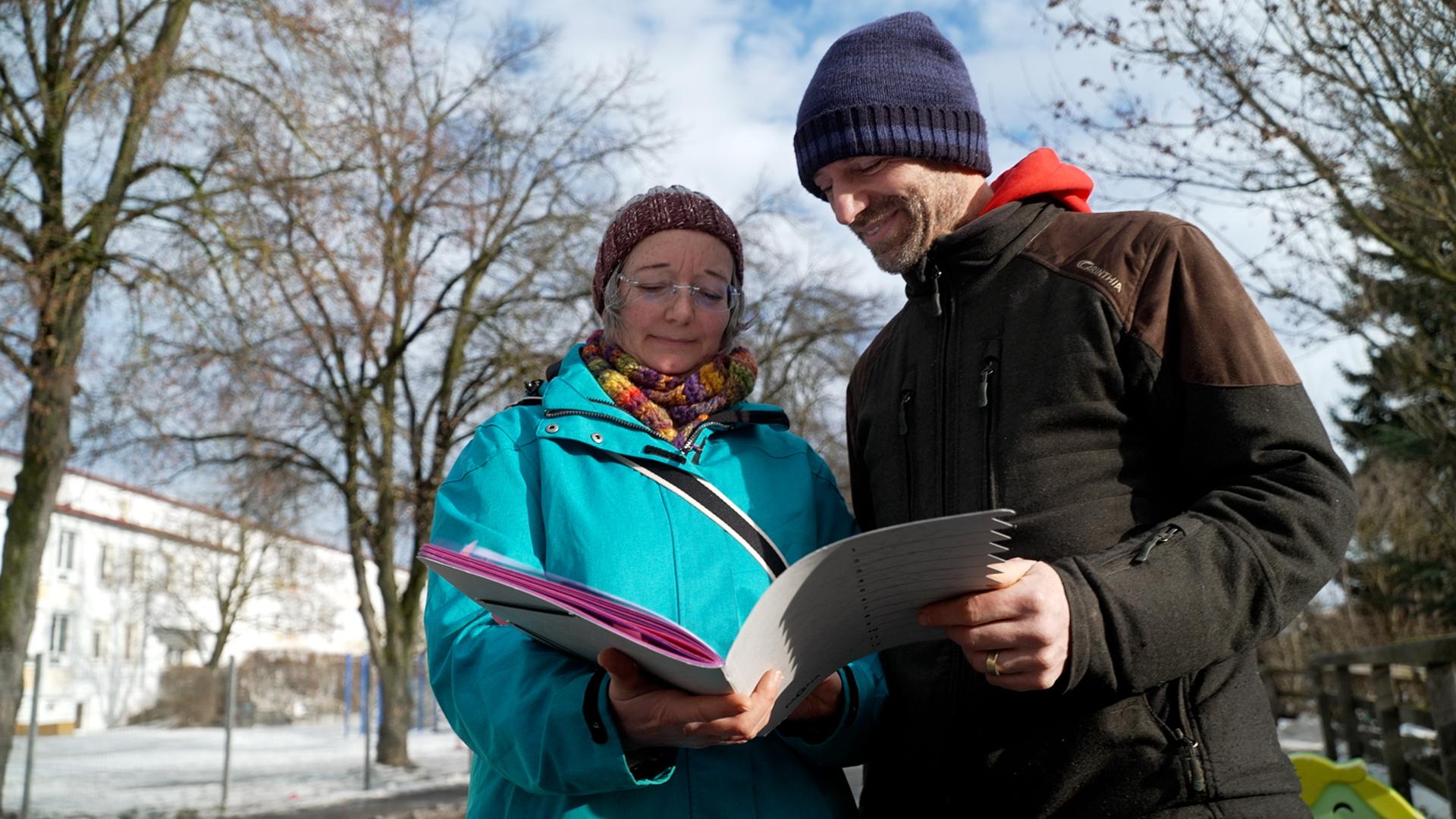 Zwei Menschen schauen in ein Heft voller Dokumente zum Thema Tempo 30.