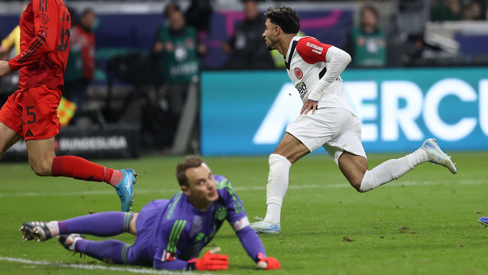 Manuel Neuer (Boden) kann dem Schuss von Omar Marmoush (rechts) nur hinterherschauen.