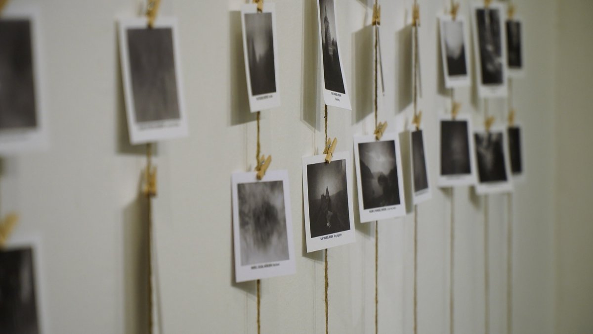 Fotos hängen an Wäscheklammern an Schnüren an einer Wand